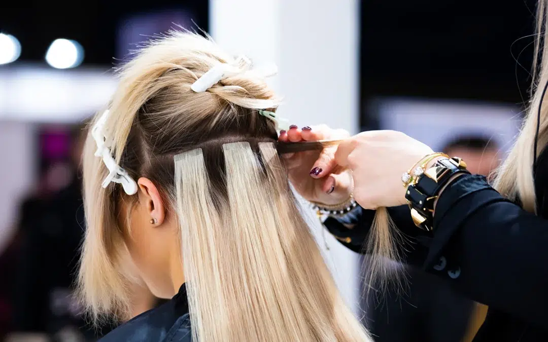 professional hairdresser making hair extensions for blonde girl