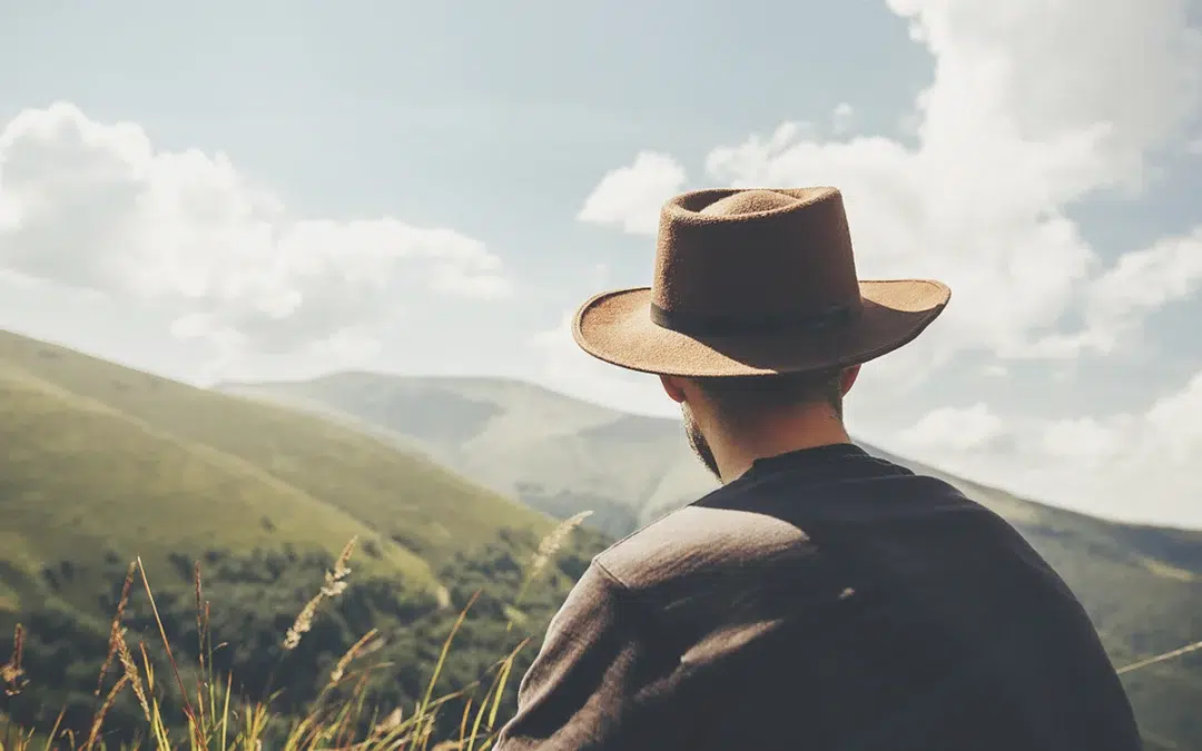stylish traveler man in hat sitting on top of sunny mountains