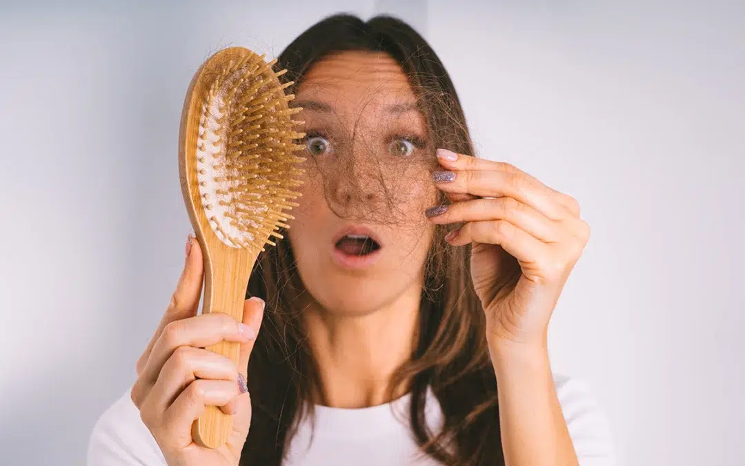woman holding hair brush and showing damaged hair