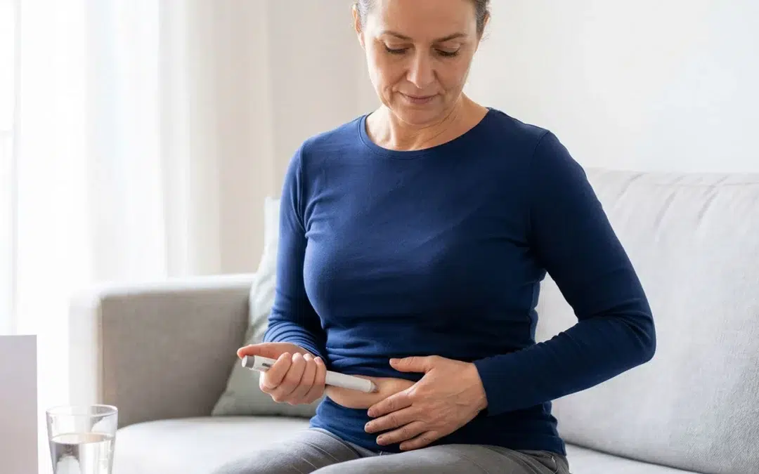 Woman sitting on a sofa administering a subcutaneous weight loss injection to her abdomen.